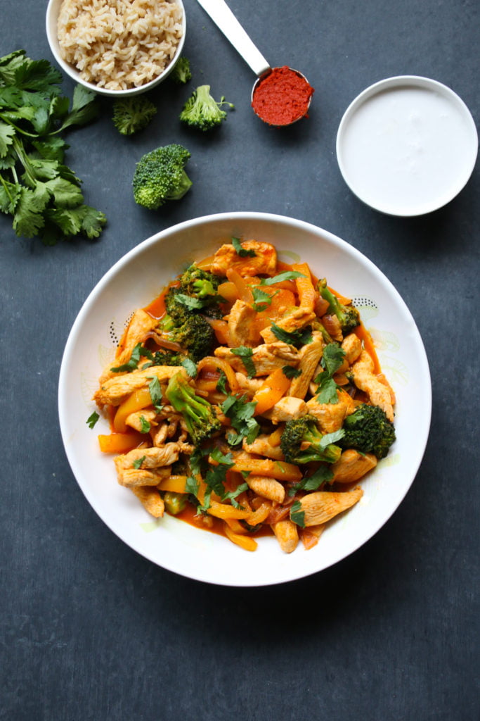 Thai chicken red curry, in a white bowl, on a black background. 