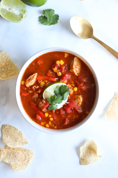 Chicken tortilla soup overhead, on a marble background, surrounded by tortilla chips. 