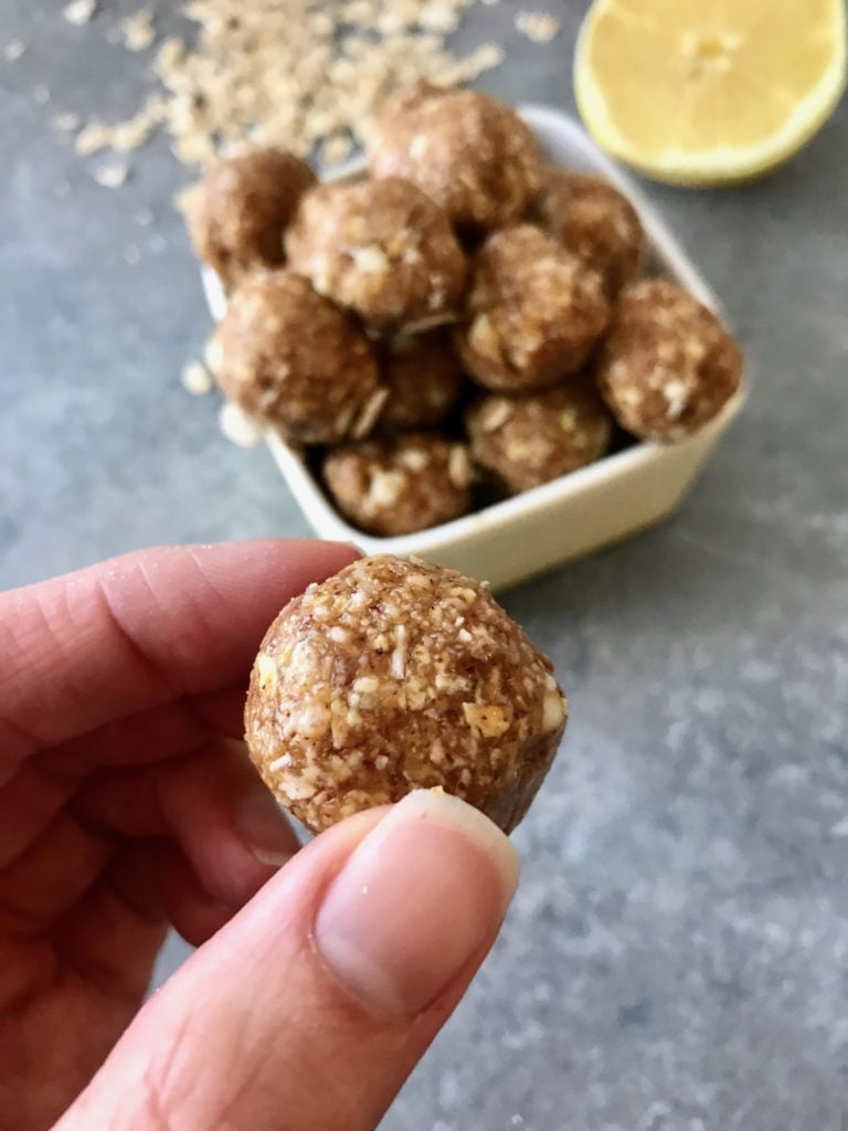 White chocolate and lemon energy balls up-close, in a white bowl on a gray background.