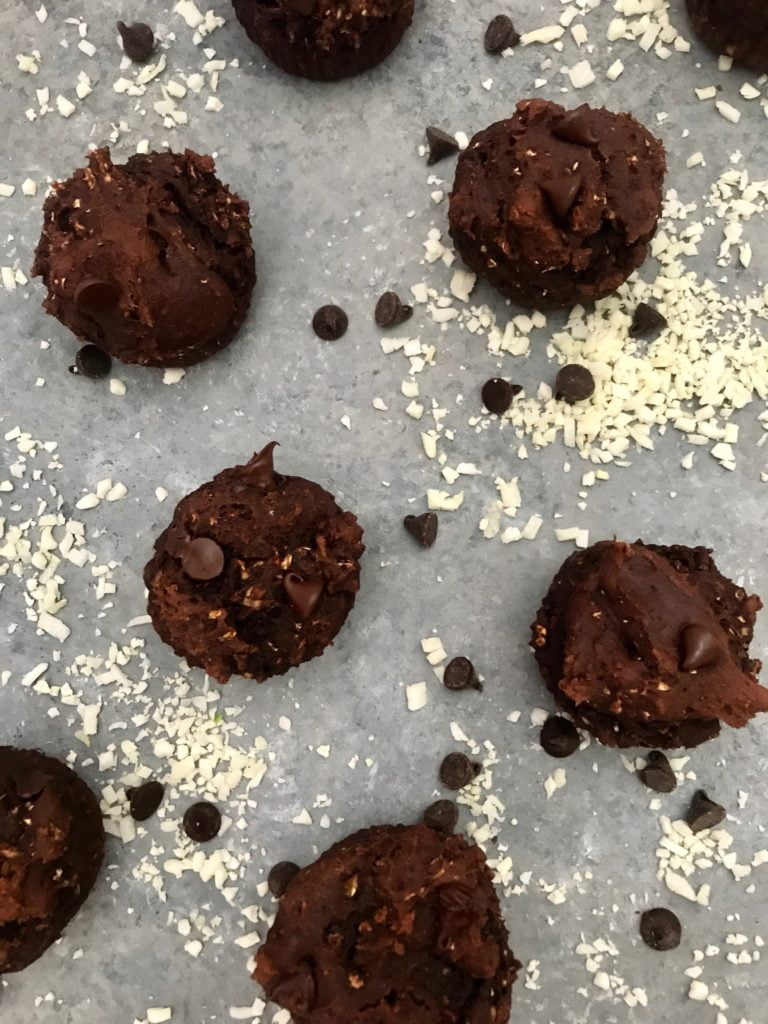 6 gluten-free double chocolate muffins on a gray background, with scattered cauliflower rice and chocolate chips scattered in between.