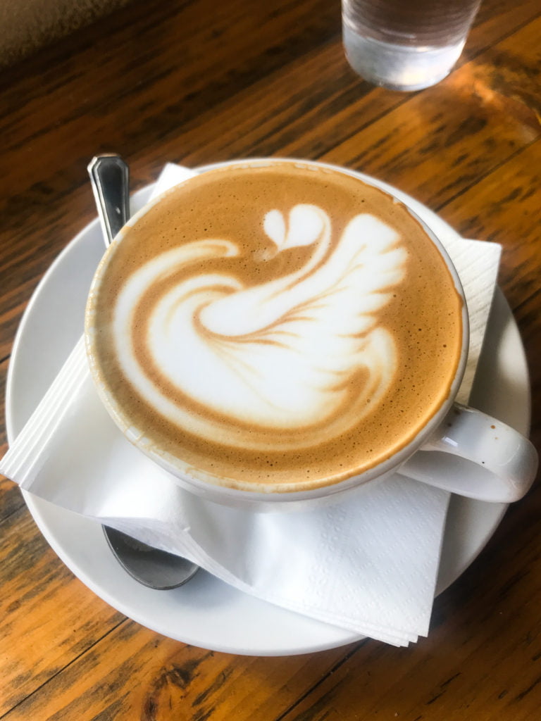 Latte in a white cup, on a white saucer. 