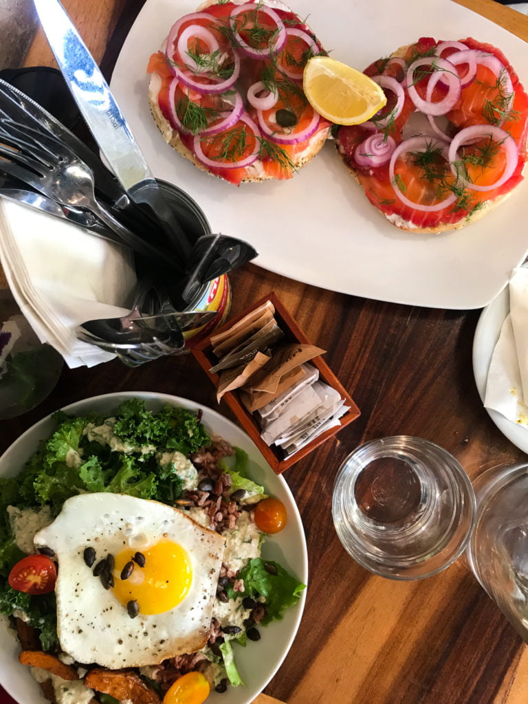 Overhead shot of bagel and lox, and greens and grain bowl topped with an egg at Cafe XOHO. 