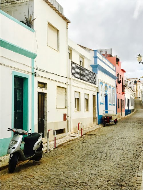 White houses accented with teal, pink and blue trim in Lagos, Portugal. 