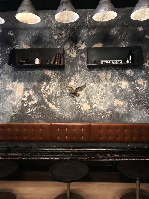 Dark brown leather banquette against navy blue washed wall at Rival Bros, Philadelphia. 