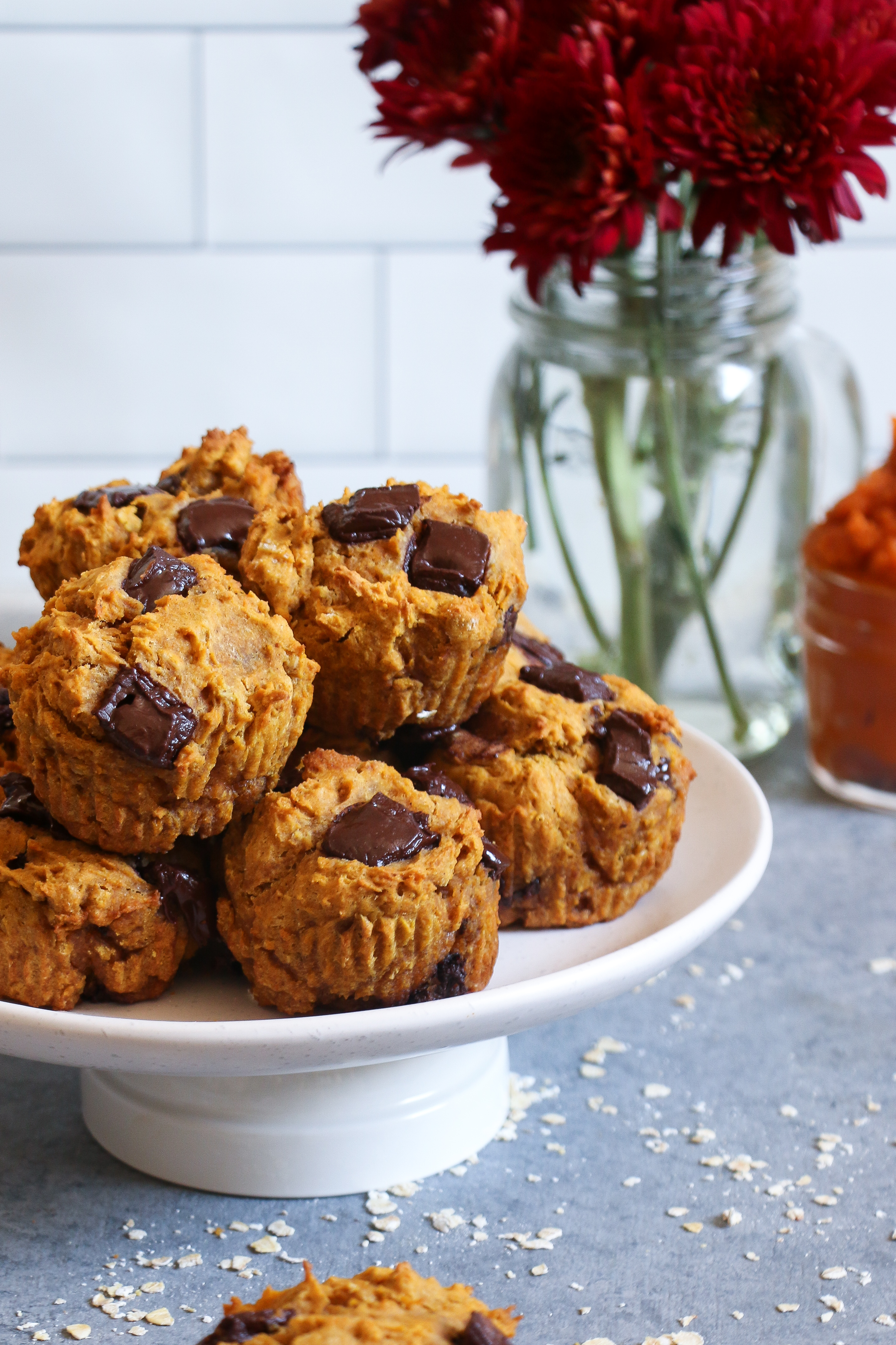 Pumpkin-chocolate chunk muffin on a white plate on a gray background. 