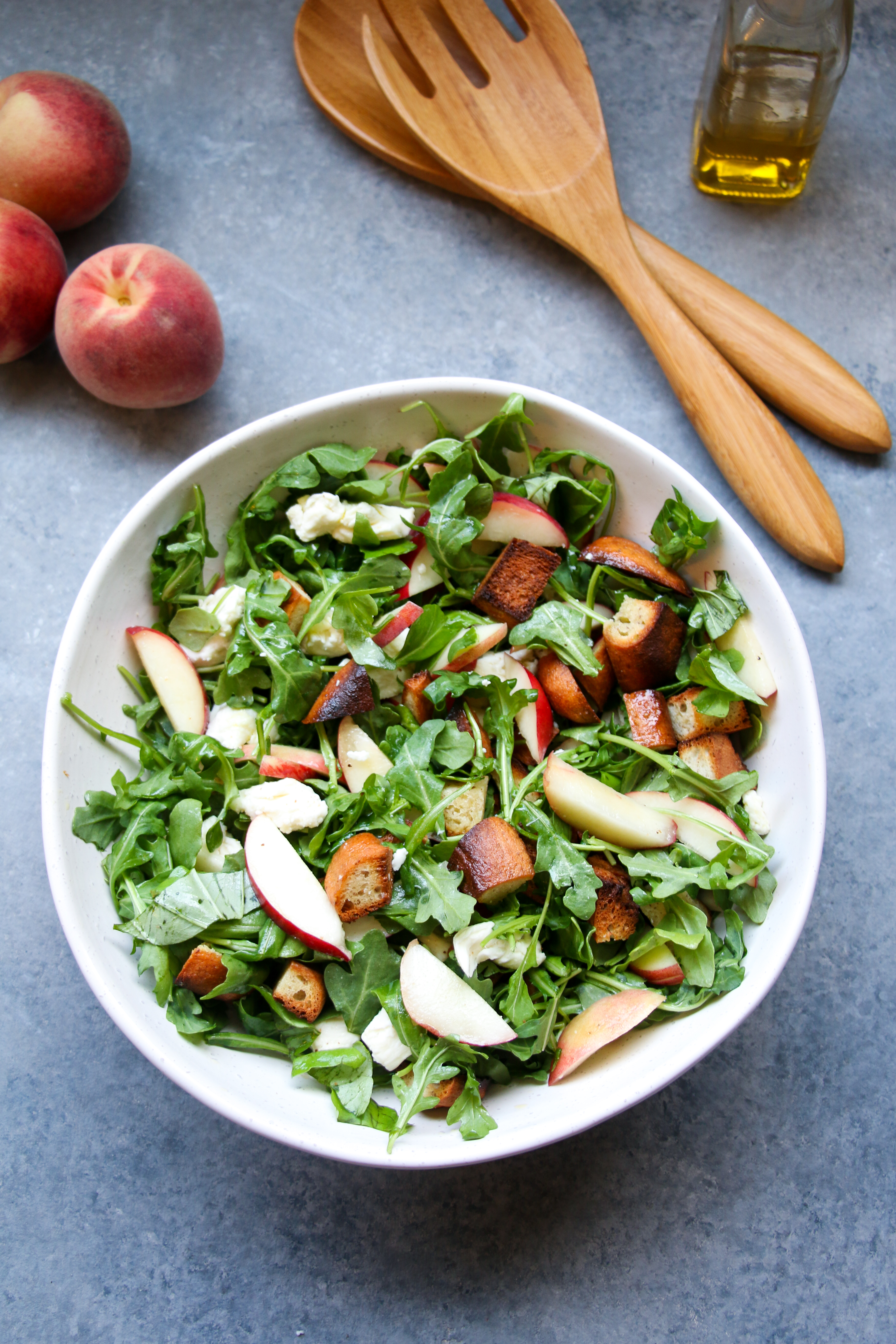 Peach panzanella salad in a white bowl on a gray background. 