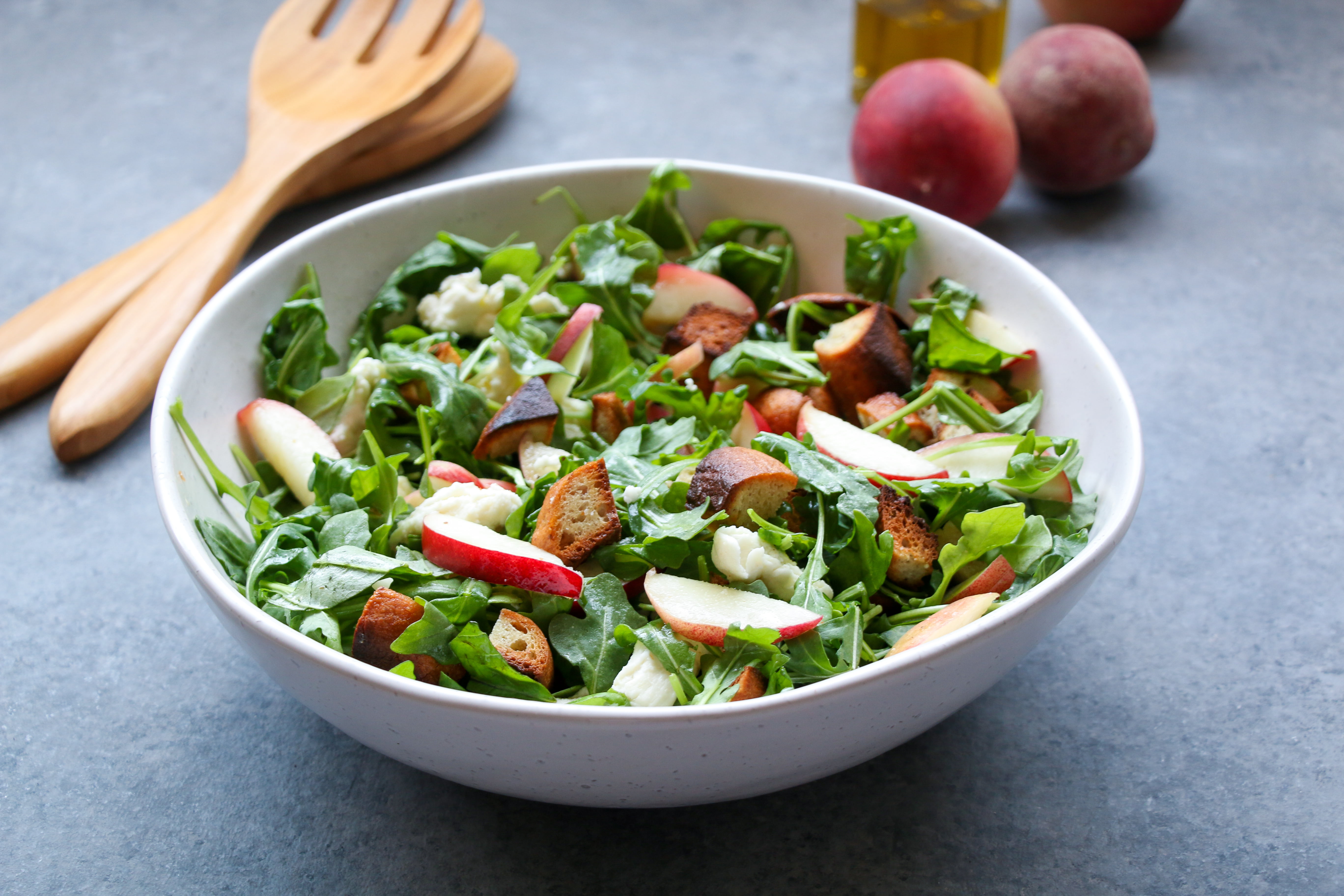 Close-up shot of peach Panzanella salad in a white bowl on a gray background