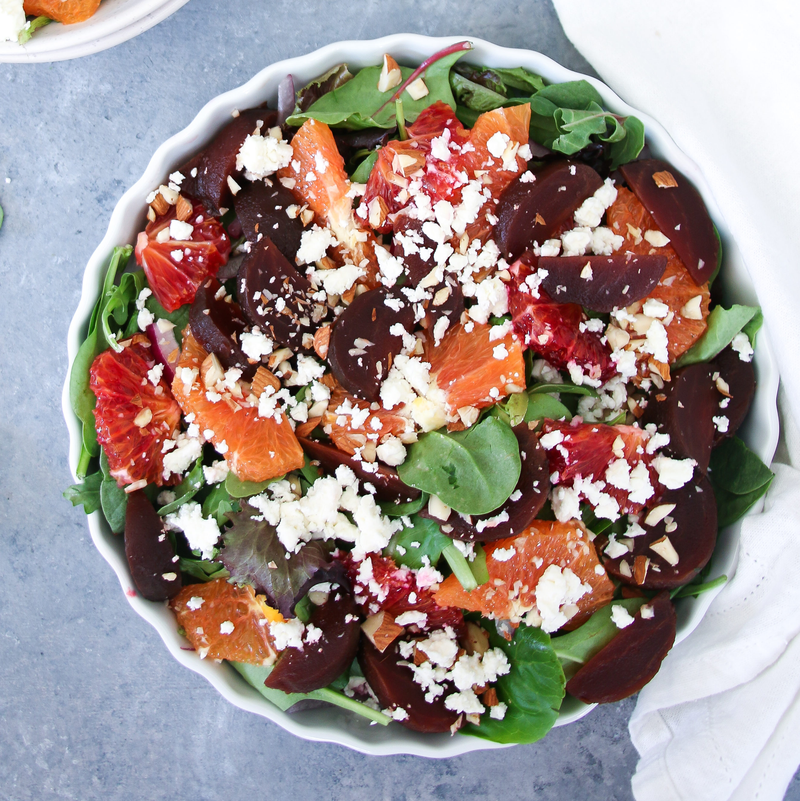 Beet, orange, and feta salad with mint dressing in a white bowl on a gray background
