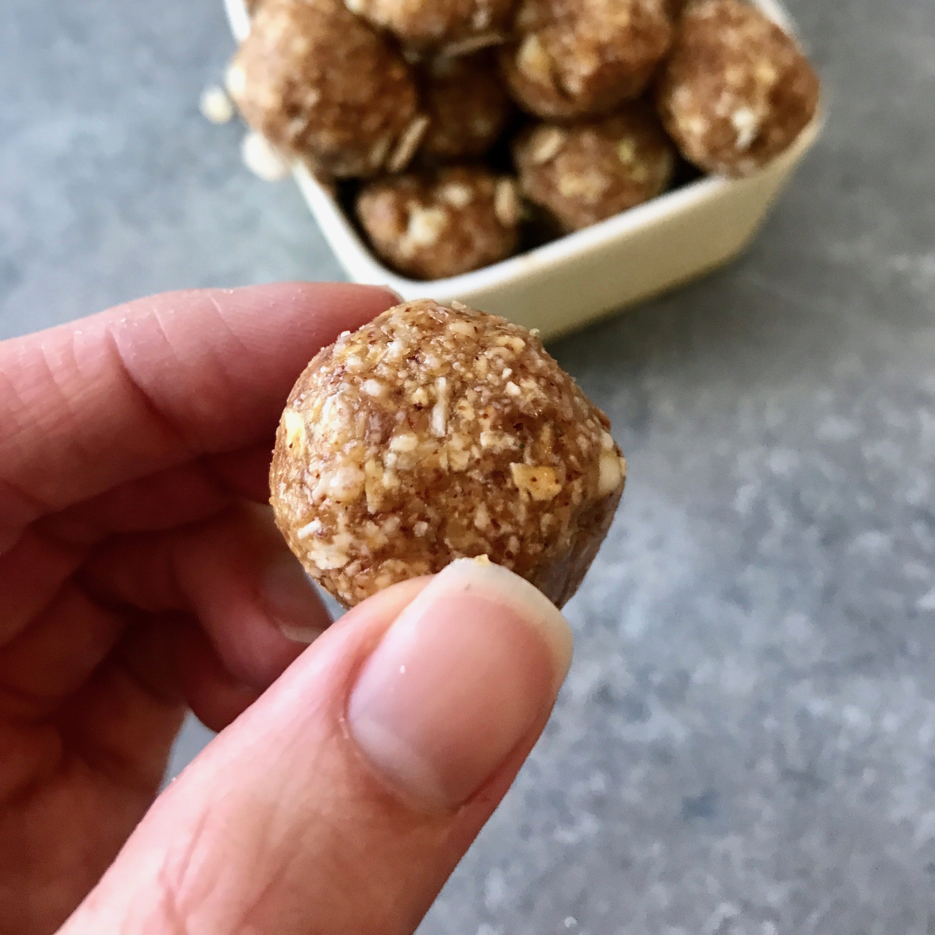 Lemon and White Chocolate Energy Bites in a small white ball on a gray background