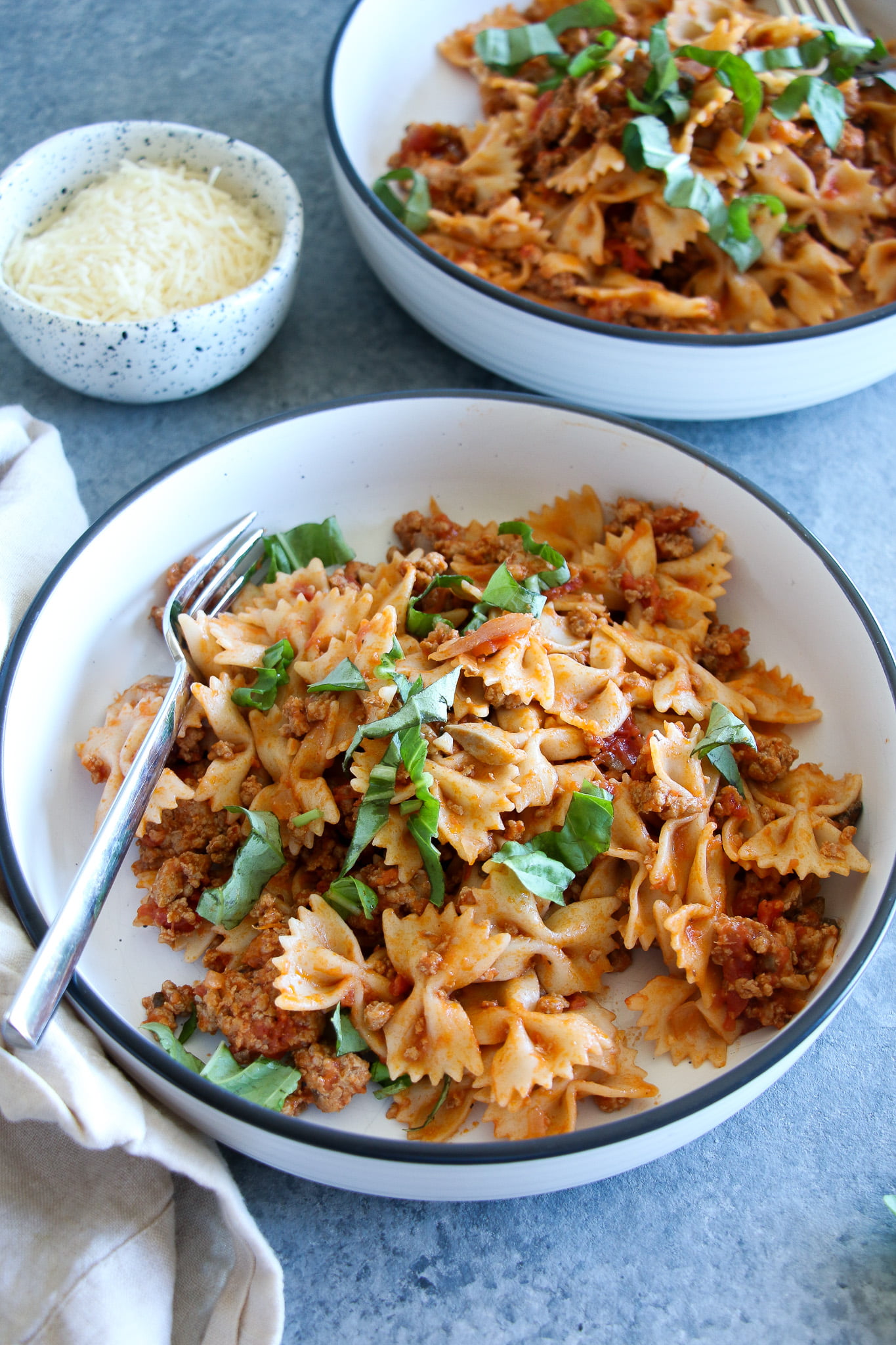 Creamy ground turkey pasta in two white bowls on a gray background. 